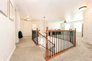 Hallway with light colored carpet and a notable chandelier