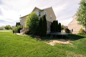 View of side of home with a trampoline and a yard