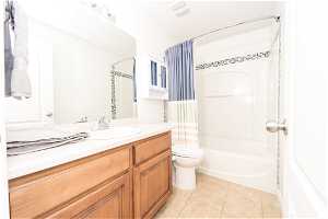 Full bathroom with tile floors, oversized vanity, shower / bath combo, and toilet