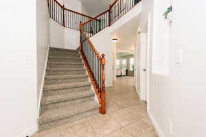 Grand staircase with light tile flooring