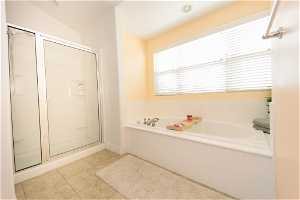 Master Bathroom featuring tile flooring, vaulted ceiling, and plus walk in shower