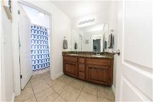 Main bathroom with tile flooring, oversized vanity, and dual sinks