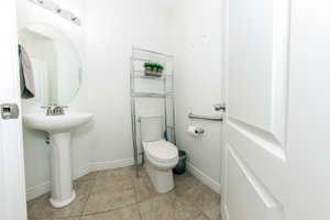 Bathroom featuring tile floors and toilet near entry way grand staircase.