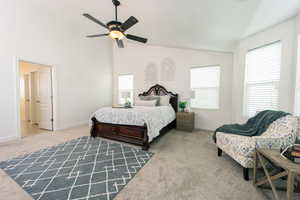 Carpeted bedroom with ceiling fan and vaulted ceiling