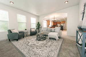 Living room featuring light colored carpet and a notable chandelier