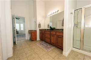 Master Bathroom with a shower with shower door, tile flooring, ceiling fan, and double sink vanity