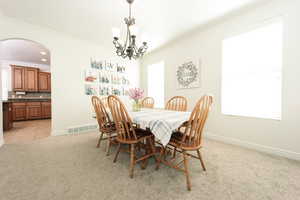 Carpeted dining space with a notable chandelier and ornamental molding