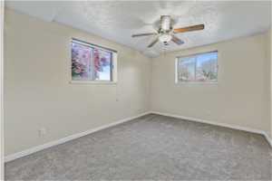 Unfurnished room featuring ceiling fan, carpet, and a textured ceiling