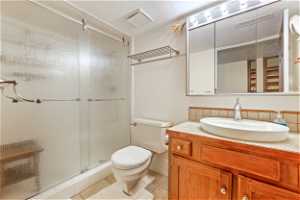 Bathroom with a shower with door, toilet, tile flooring, a textured ceiling, and vanity