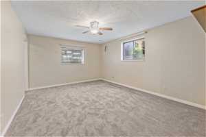 Empty room featuring carpet, ceiling fan, and a textured ceiling
