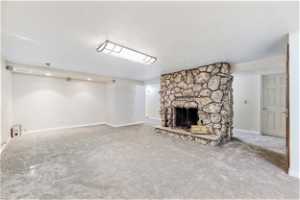 Unfurnished living room featuring carpet, a fireplace, and a textured ceiling