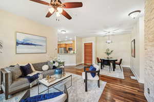 Living room with ceiling fan and dark wood-type flooring