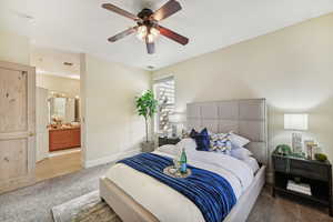 Bedroom with ensuite bath, ceiling fan, and carpet floors