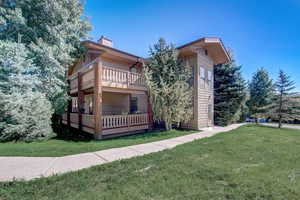 Back of house with a deck and a lawn