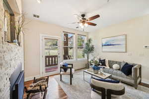 Living room with ceiling fan, hardwood / wood-style flooring, and a fireplace