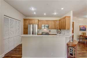 Kitchen with backsplash, kitchen peninsula, stainless steel appliances, and dark hardwood / wood-style floors