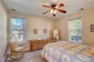 Bedroom with carpet, ceiling fan, and multiple windows