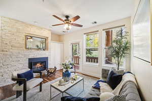 Living room featuring a stone fireplace, hardwood / wood-style flooring, and ceiling fan