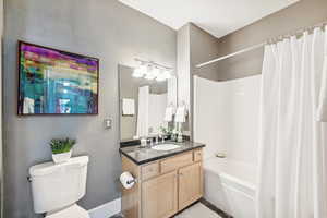 Full bathroom with vanity, toilet, and shower / bathtub combination with curtain