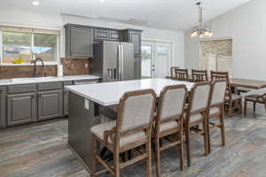 Kitchen with pendant lighting, stainless steel fridge with ice dispenser, backsplash, sink, and dark hardwood / wood-style flooring