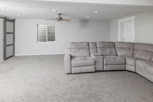 Living room with carpet flooring, a barn door, and ceiling fan