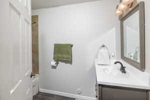 Bathroom with tiled shower / bath combo, hardwood / wood-style floors, and vanity