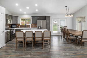 Kitchen with a center island, tasteful backsplash, stainless steel appliances, dark hardwood / wood-style floors, and vaulted ceiling