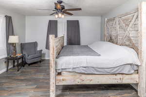 Primary bedroom with dark hardwood / wood-style flooring, ceiling fan, and a textured ceiling