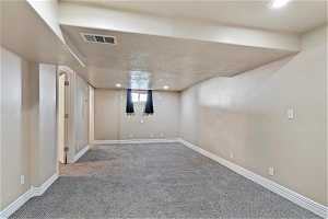 Basement with a textured ceiling and carpet flooring