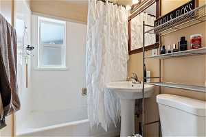 Bathroom with toilet and shower / bathtub combination with curtain