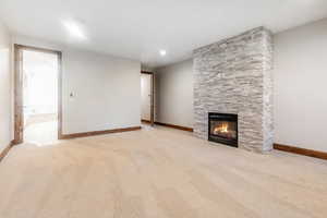 Unfurnished living room with a fireplace and light carpet