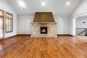 Unfurnished living room with a wealth of natural light, a tile fireplace, lofted ceiling, and light hardwood / wood-style flooring