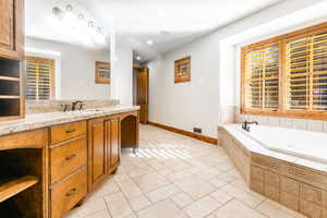 Bathroom with tiled bath, tile flooring, and vanity