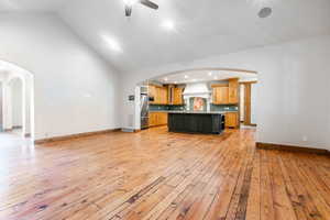 Unfurnished living room with light hardwood / wood-style flooring, ceiling fan, sink, and high vaulted ceiling