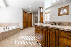 Bathroom featuring tiled bath, vanity, and tile floors