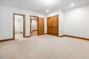 Unfurnished bedroom with a closet, light carpet, and ensuite bathroom