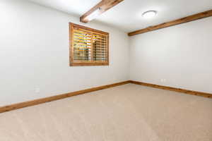 Unfurnished room with beam ceiling and carpet floors