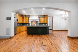 Kitchen with light hardwood / wood-style floors, an inviting chandelier, premium range hood, and backsplash