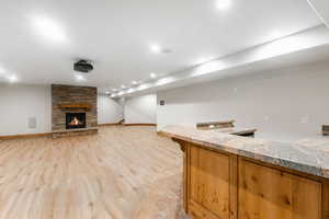 Kitchen featuring light hardwood / wood-style flooring, a stone fireplace, and light stone counters