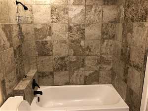 Bathroom with tiled shower / bath and toilet