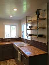 Kitchen with butcher block countertops, sink, stainless steel dishwasher, and dark brown cabinets