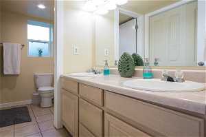 Bathroom with large vanity, tile floors, toilet, and double sink