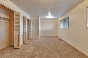 Unfurnished bedroom with light carpet and a textured ceiling