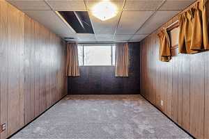 Spare room featuring wooden walls, carpet flooring, and a paneled ceiling