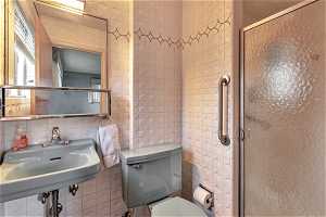 Bathroom with walk in shower, toilet, and tile walls