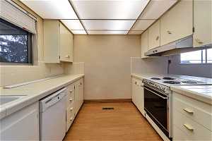 Kitchen featuring backsplash, light hardwood / wood-style floors, tile countertops, and white appliances