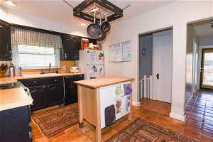 Kitchen featuring black dishwasher, white fridge, wooden counters, sink, and hardwood / wood-style flooring
