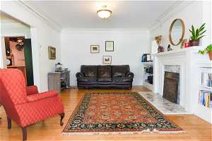 Living room featuring hardwood / wood-style flooring, ornamental molding, and a tile fireplace
