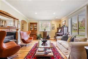 Living room with hardwood / wood-style floors, crown molding, and a high end fireplace