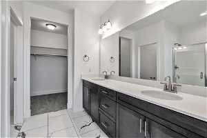 Bathroom featuring dual sinks, a shower with door, tile floors, and large vanity